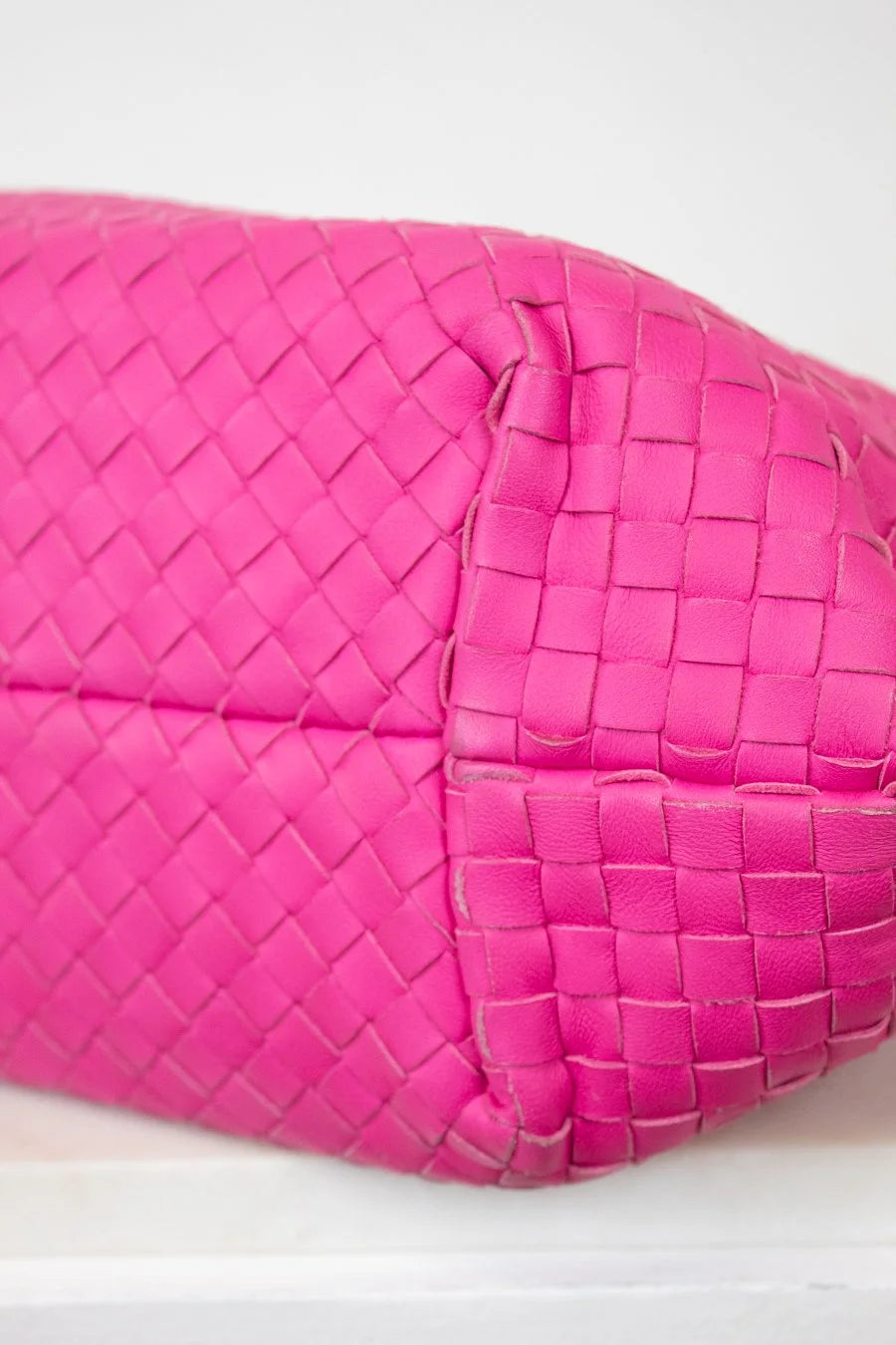 Pink woven handbag on a white background