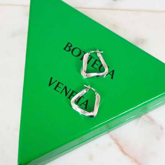 Silver hoop earrings on a Bottega Veneta green triangle box.