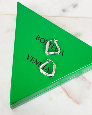 Silver hoop earrings on a Bottega Veneta green triangle box.