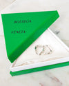 Silver earrings in a Bottega Veneta box on a marble surface