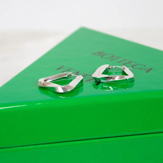 Silver hoop earrings on a green box with 'Bottega Veneta' branding.
