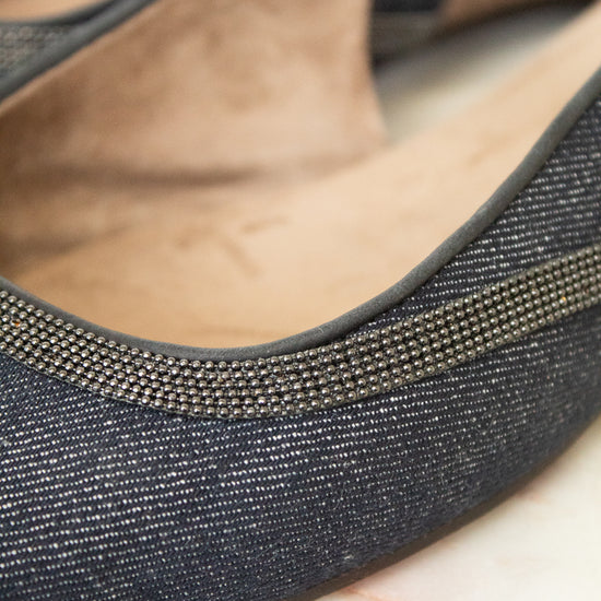 Close-up of a single women's flat shoe with a dark charcoal gray textured fabric upper, a thin metallic silver rhinestone trim along the edge, and a tan suede-like insole.