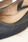 Close-up of a single women's flat shoe with a dark charcoal gray textured fabric upper, a thin metallic silver rhinestone trim along the edge, and a tan suede-like insole.