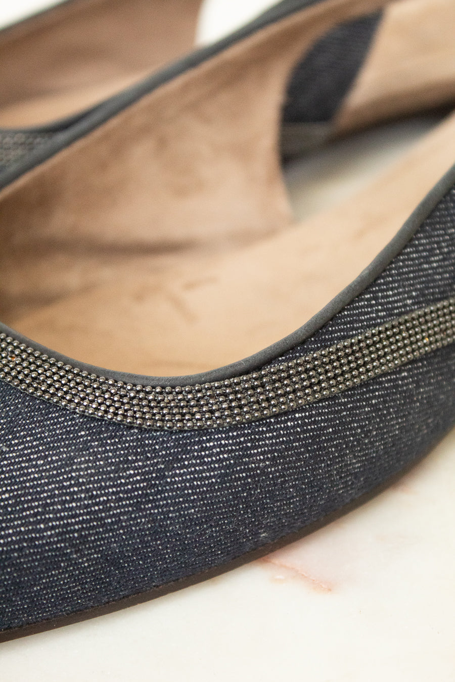Close-up of a single women's flat shoe with a dark charcoal gray textured fabric upper, a thin metallic silver rhinestone trim along the edge, and a tan suede-like insole.