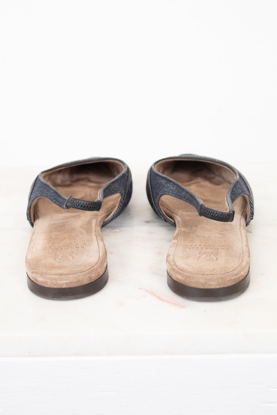 A pair of women's open-toe mule sandals with dark blue-gray textured straps and tan suede-like footbeds, shown from the back on a white surface.