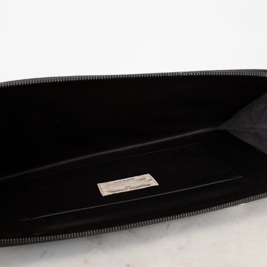 Black clutch with a brand logo on a marble surface