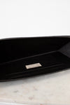 Black clutch with a brand logo on a marble surface