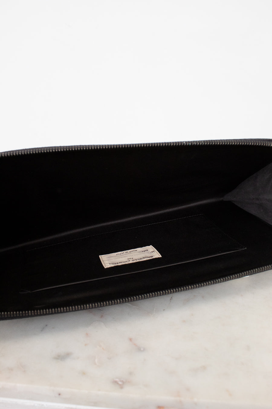 Black clutch with a brand logo on a marble surface