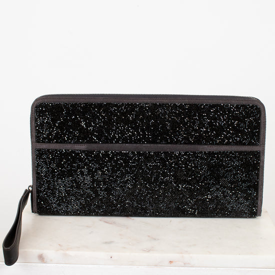 Black glittery clutch bag on a white marble surface