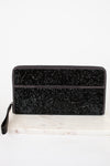 Black glittery clutch bag on a white marble surface