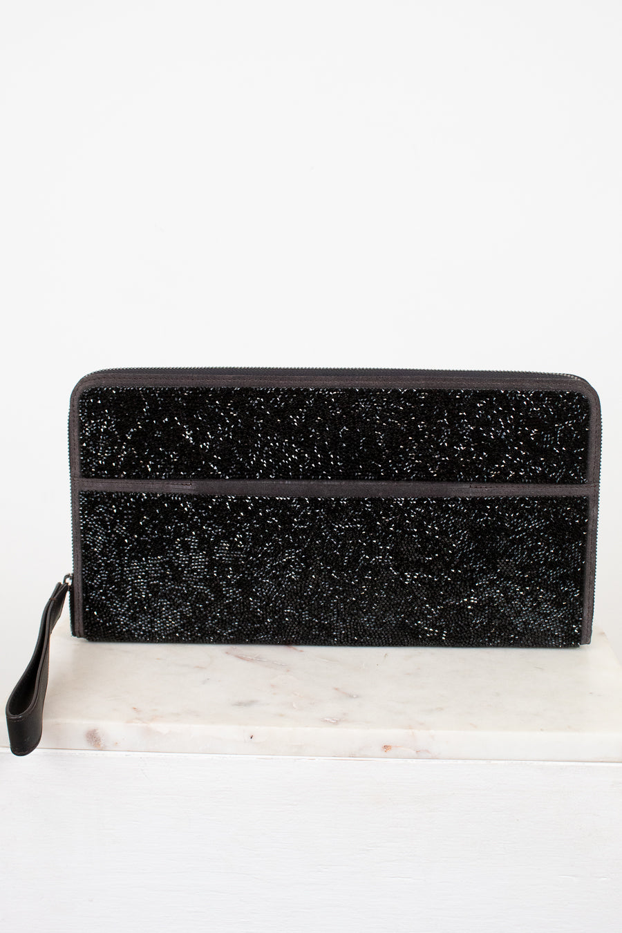Black glittery clutch bag on a white marble surface