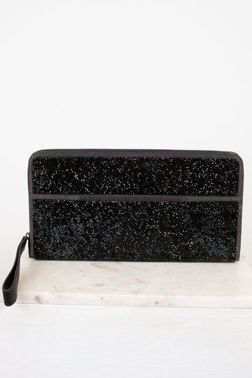 Black glittery clutch bag on a white marble surface