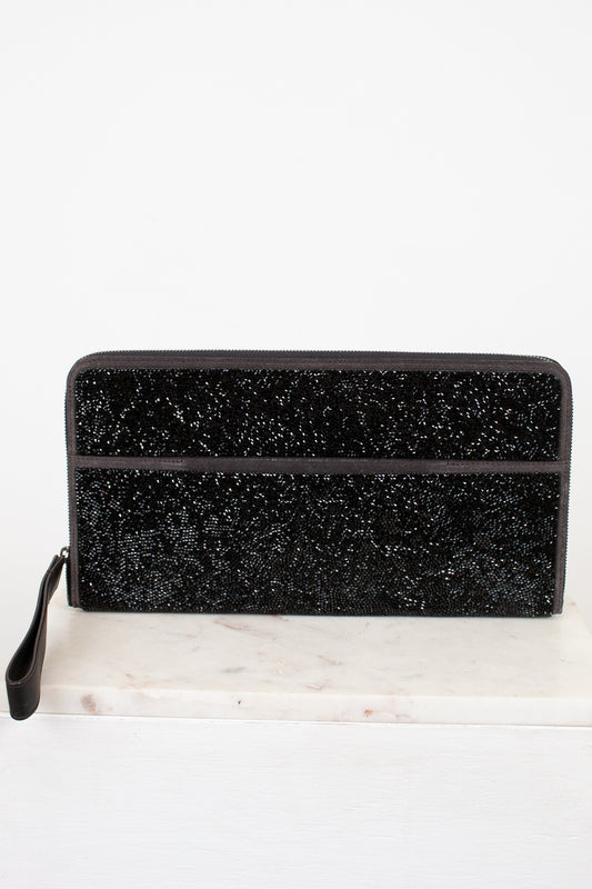 Black glittery clutch bag on a white marble surface