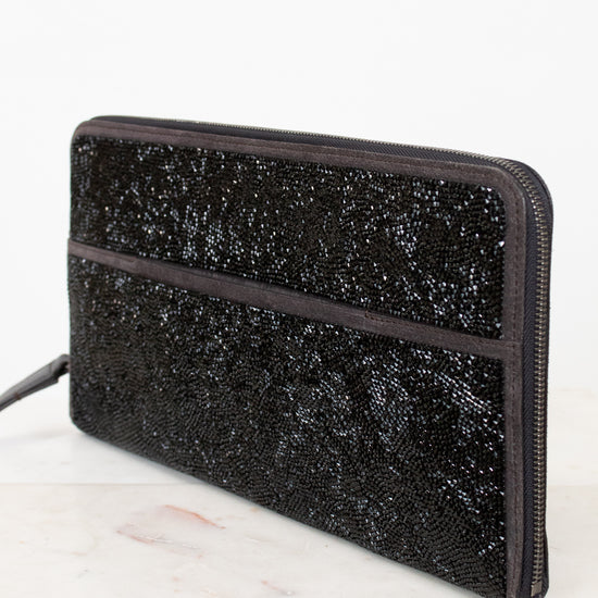 Black glittery clutch bag on a white surface