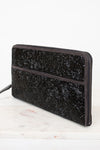 Black glittery clutch bag on a white surface