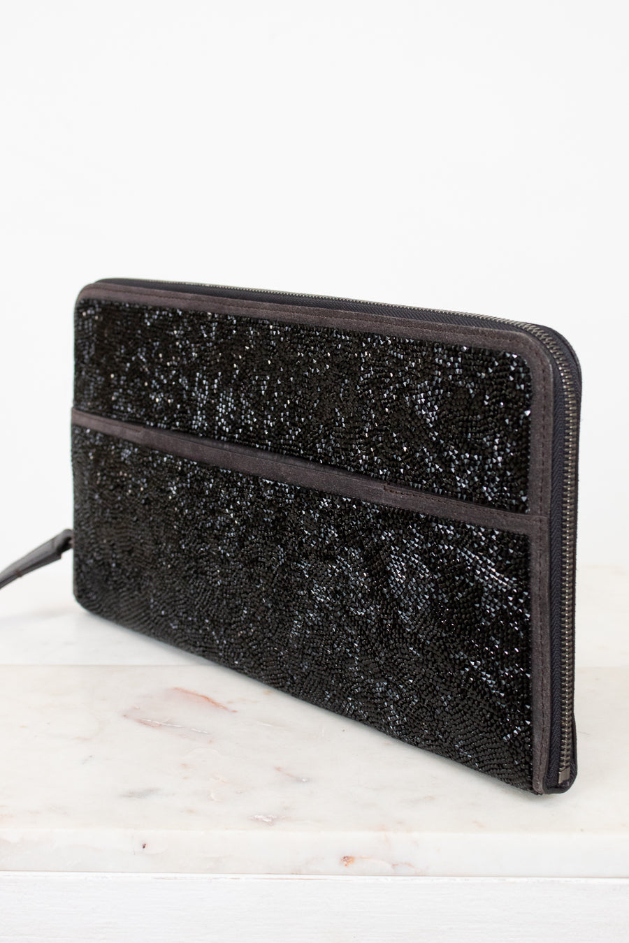 Black glittery clutch bag on a white surface