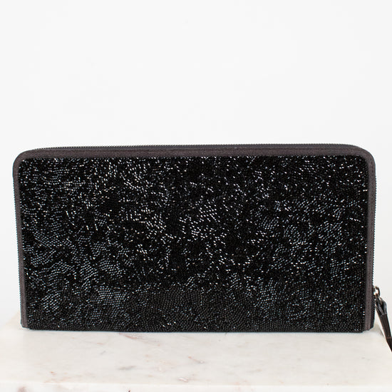 Black glittery clutch bag on a white marble surface with a white background