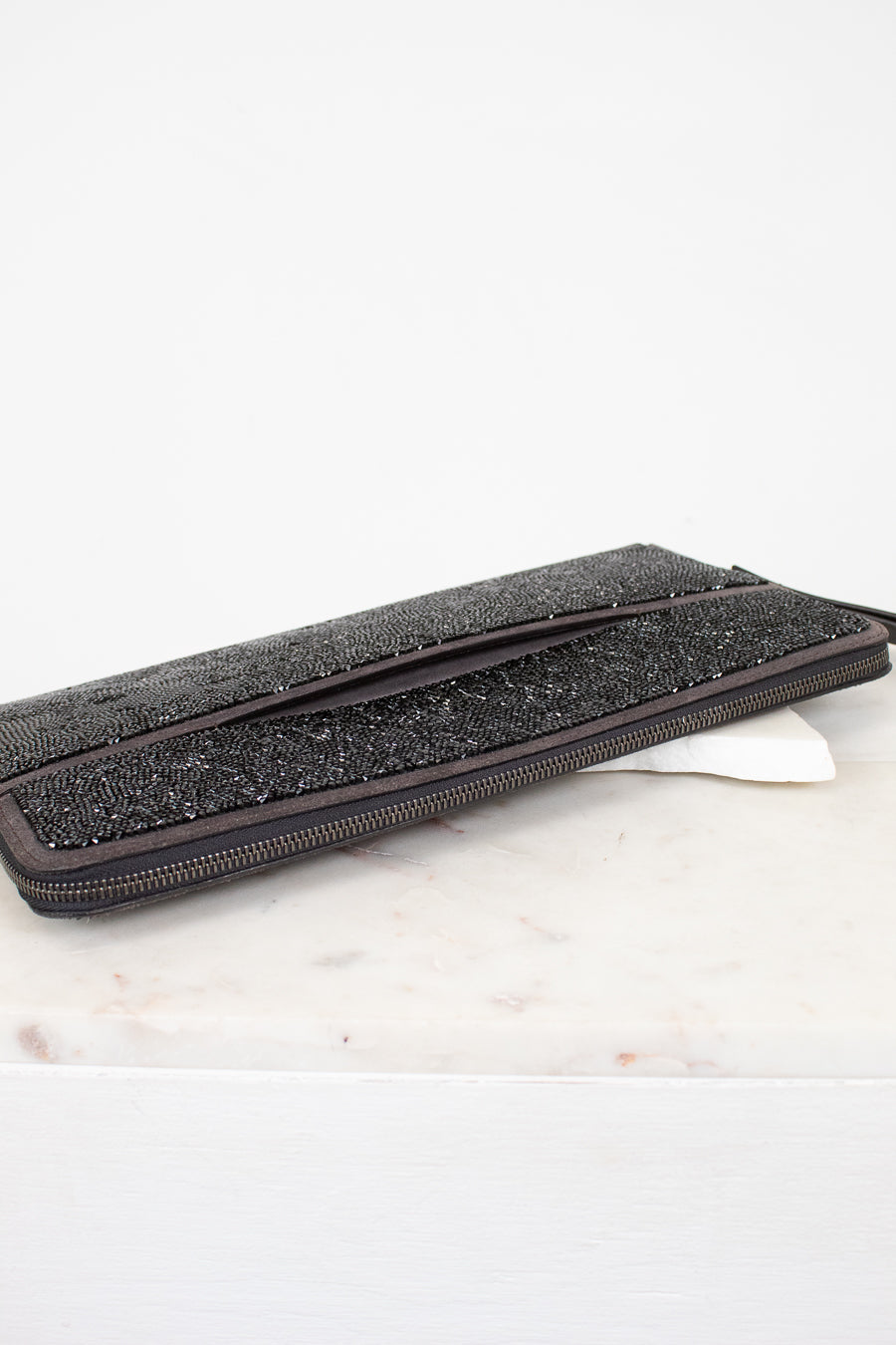 Black glittery clutch bag on a marble surface