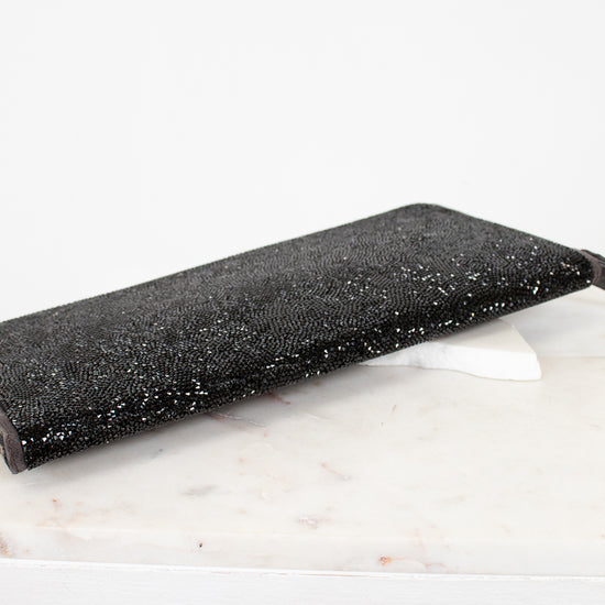 Black glittery clutch bag on a white marble surface