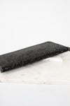 Black glittery clutch bag on a white marble surface