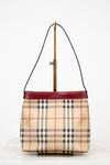 Designer handbag with check pattern and red accents on a white background