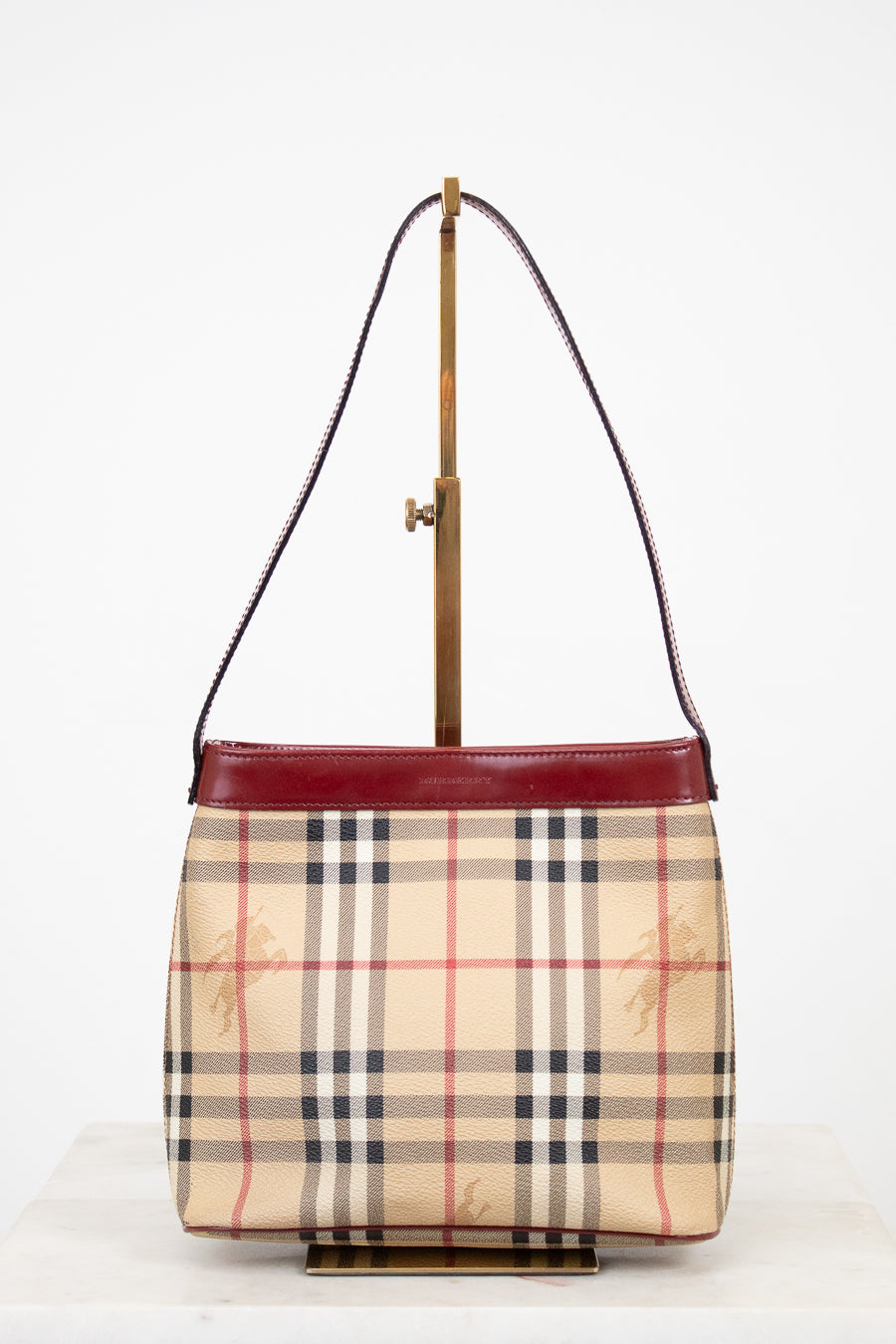 Designer handbag with check pattern and red accents on a white background