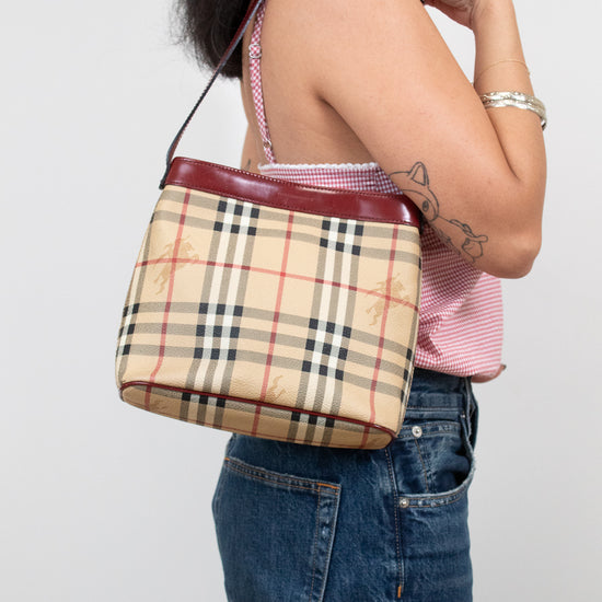 Person holding a Burberry checkered handbag against a plain background