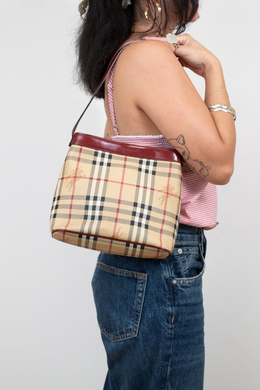 Person holding a Burberry checkered handbag against a plain background