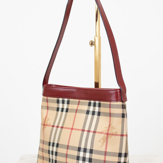 Designer handbag with check pattern and brown leather strap on a white background