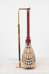 Side view of designer bag with checkered plaid print and red strap on white background