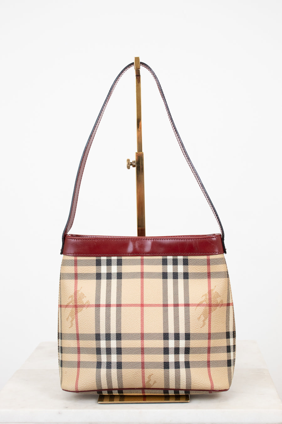 Designer handbag with check pattern and red accents on a white background