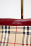 Close-up of a Burberry handbag with checkered pattern and red leather trim.