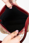 Close-up of a hand holding an open red handbag with a checkered pattern.