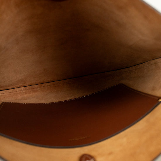 Close-up of a brown leather bag with visible stitching and brand logo.
