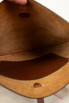 Close-up of a brown leather bag with visible stitching and brand logo.