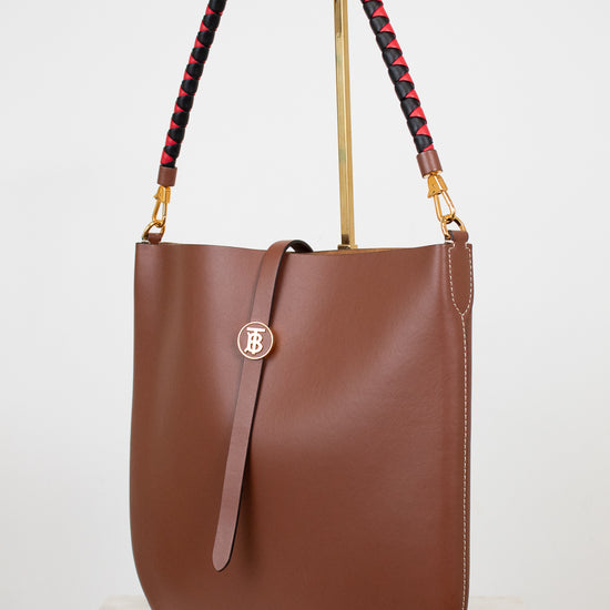 Brown handbag with a decorative strap on a white background