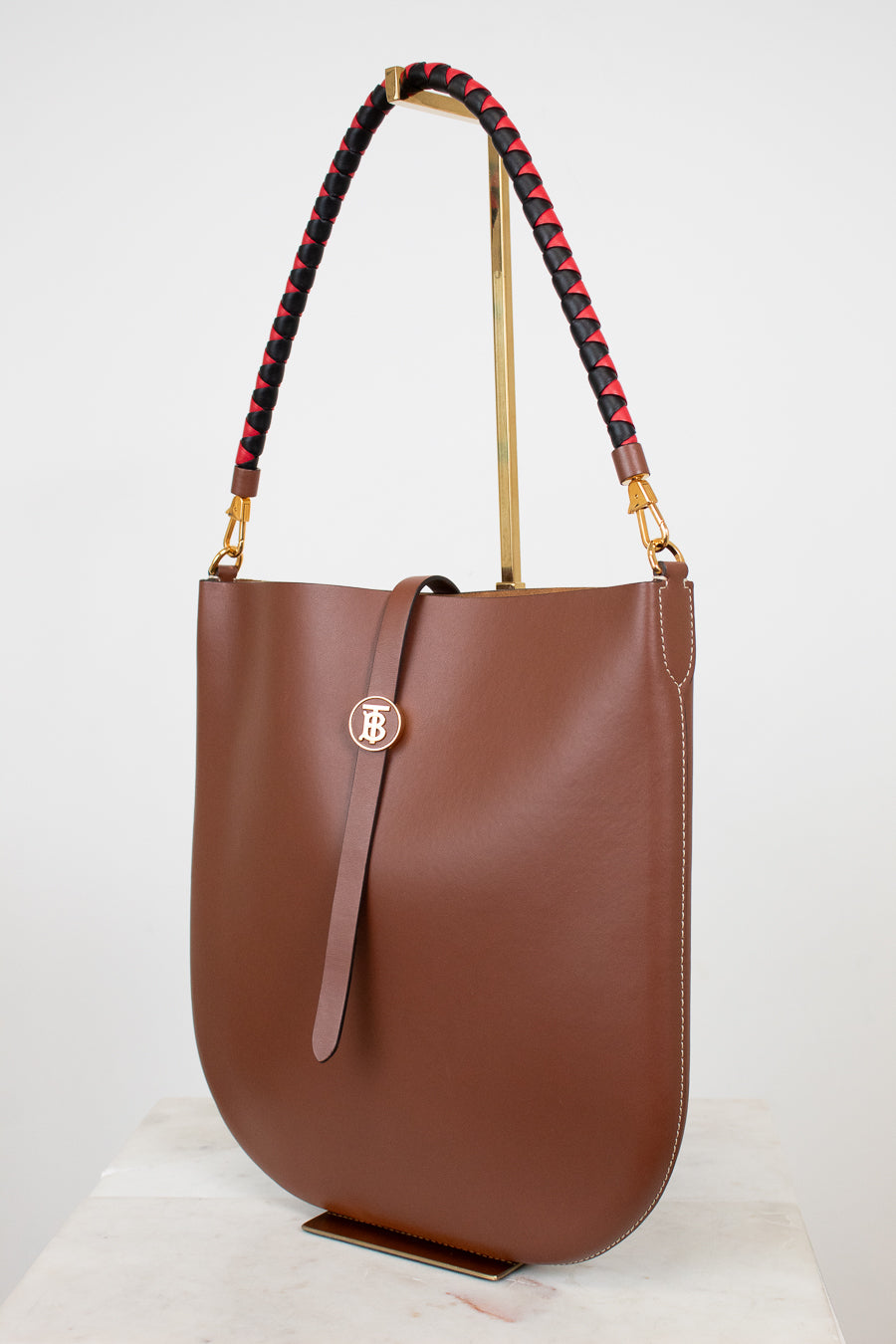 Brown handbag with a decorative strap on a white background