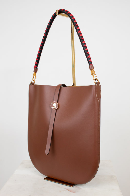 Brown handbag with a decorative strap on a white background