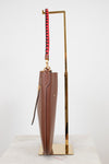 Brown umbrella with a red and black handle on a gold stand against a white background