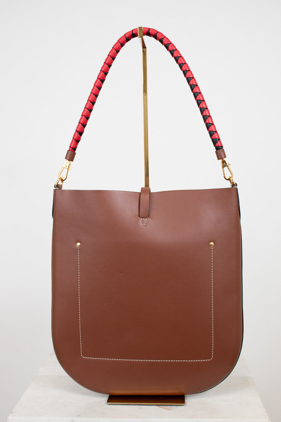 Brown leather handbag with red and black patterned handle on a white background