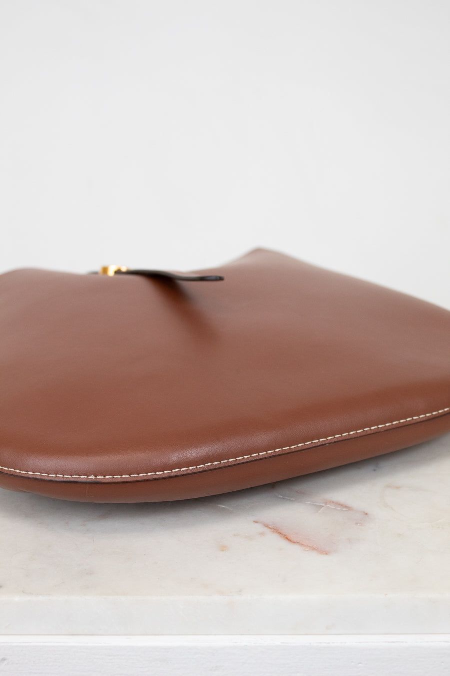 Brown leather base of purse on a light marble surface
