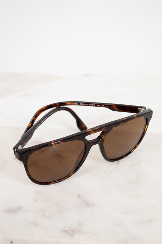 Sunglasses with tortoiseshell frame and brown lenses on a light background
