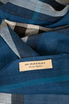 A close-up of a Burberry scarf in a blue plaid pattern with a beige brand label sewn onto it.