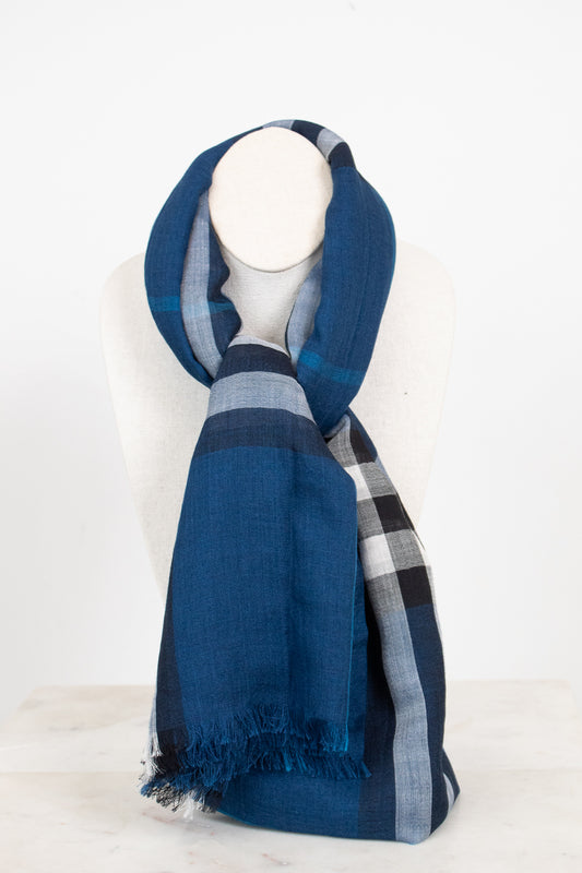 A blue plaid scarf with fringed edges, draped on a white mannequin neck against a clean white background.