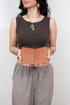 Woman holding a brown leather passport holder against a plain background