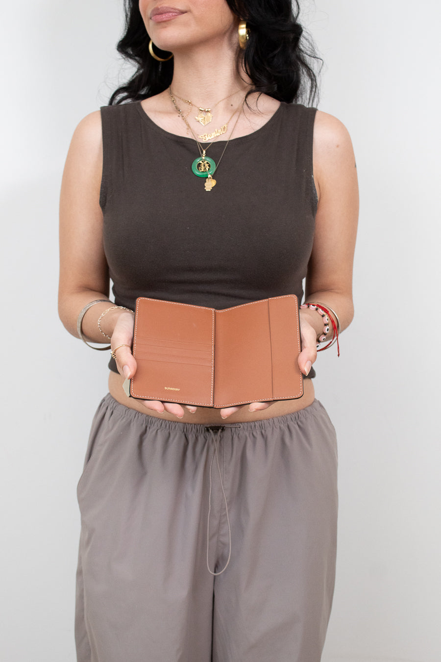 Woman holding a brown leather passport holder against a plain background