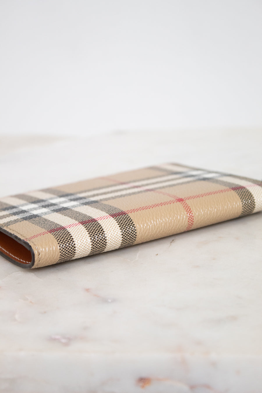 Plaid patterned passport holder on a marble surface