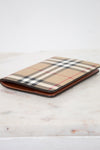 Plaid patterned passport holder with brown leather trim on a light wooden surface