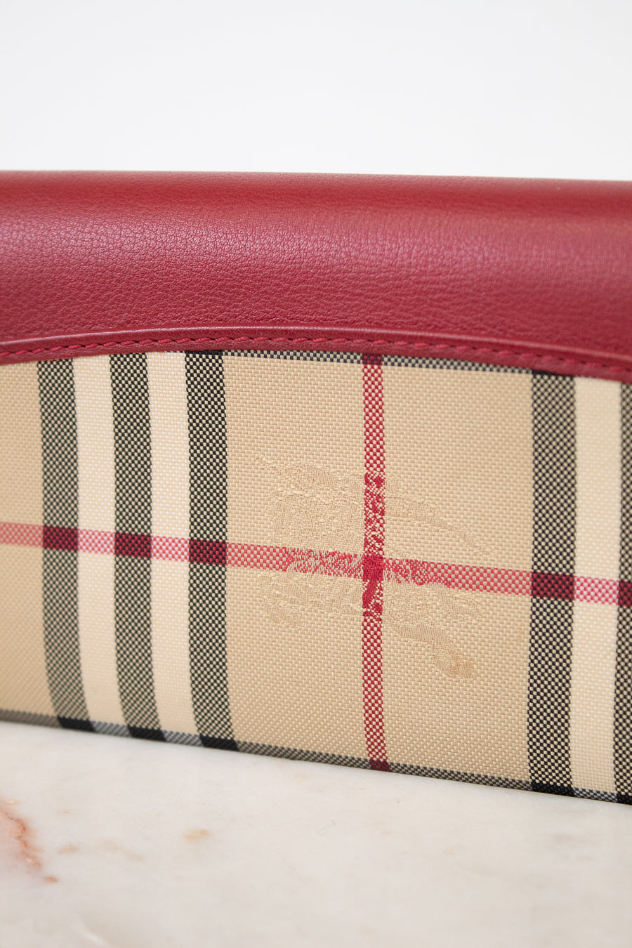 Close-up of a wallet with plaid pattern and red leather trim on a white background