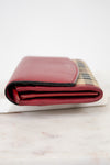 Folded red leather wallet with checkered pattern on a marble surface